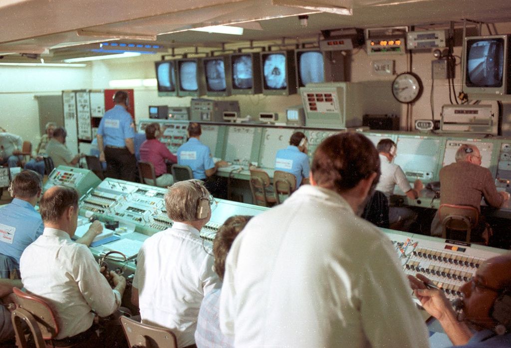 Historical spacecraft launch control room with mission personnel monitoring consoles and displays during operations.