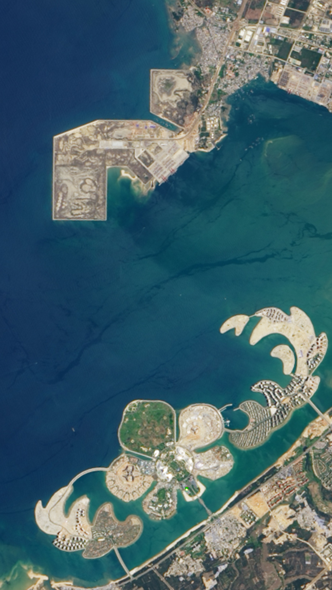 A Landsat satellite image featuring tan and green man-made islands resembling the shapes of a flower and leaves