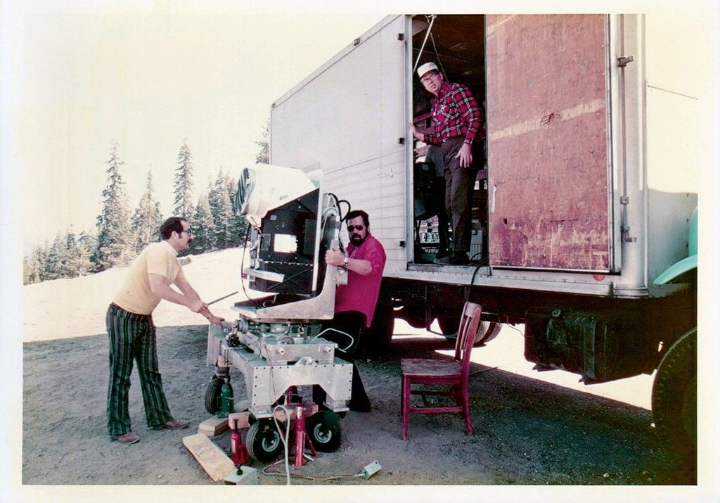 Two men move the MSS engineering model. A technician stands on the truck wearing a red shirt.