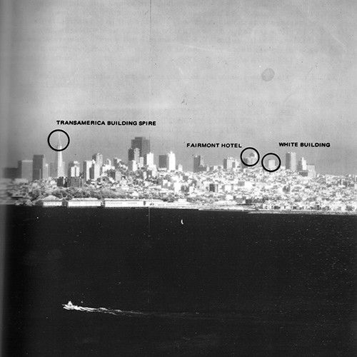 A black and white image of the San Francisco skyline with the bay in the foreground.