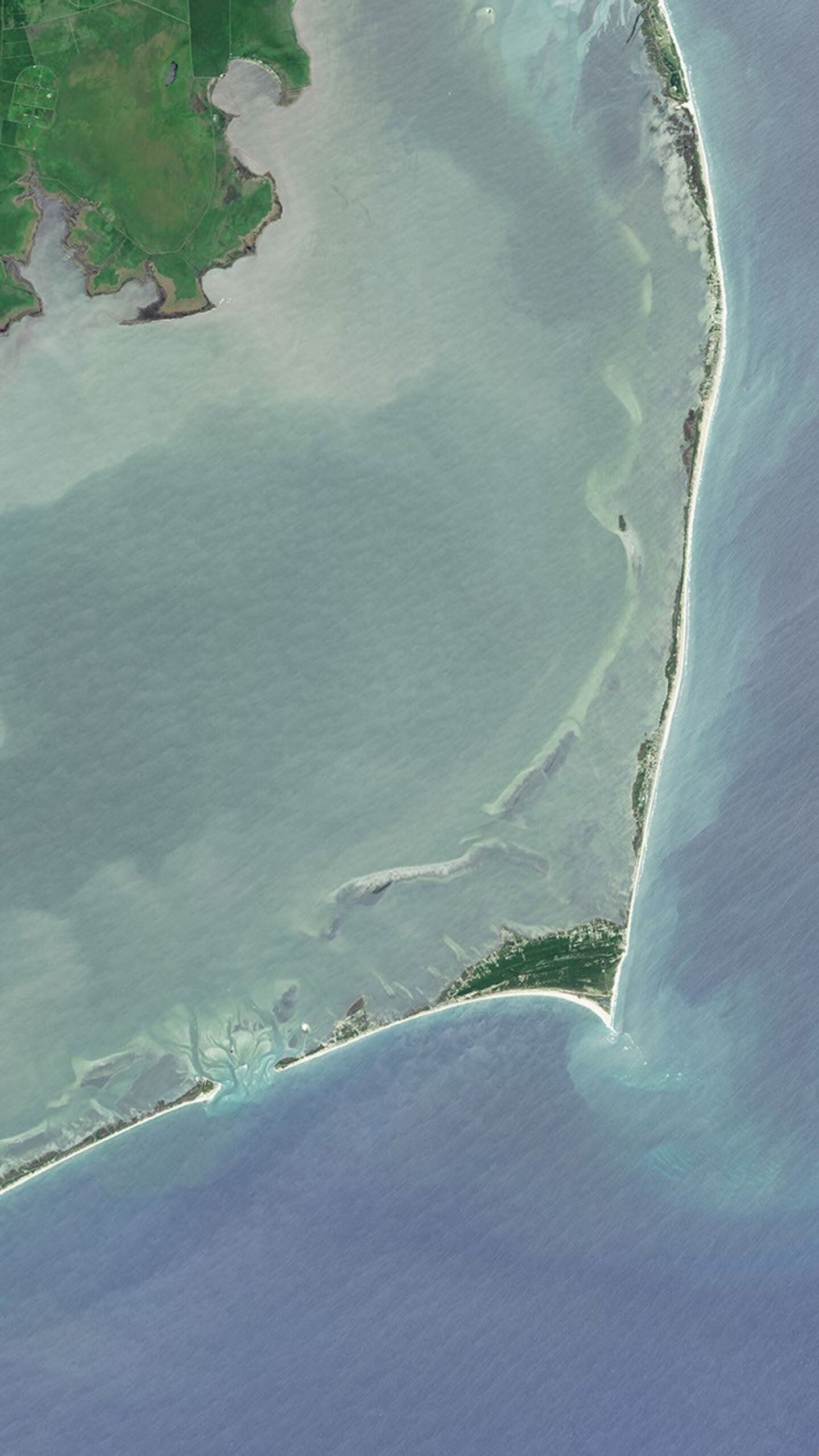 Natural-color Landsat 8 image of Cape Hatteras in North Carolina, acquired on June 7, 2015. Various stages of island evolution�from build-up to erosion�are all visible along the island chain. In the image, water appears light blue, vegetation appears green, and the sands along the cape appear white.