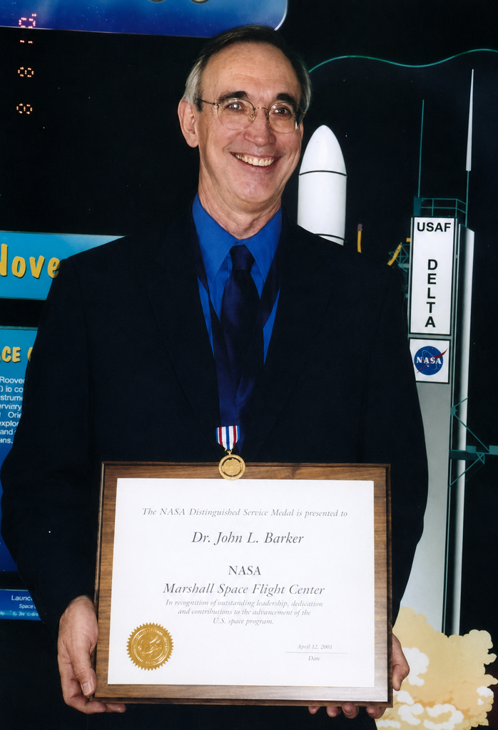 A photograph of John Barker holding an award.