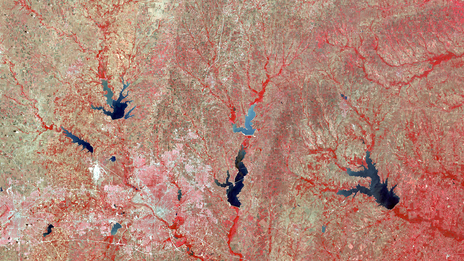 Landsat 1's first satellite image of Dallas-Fort Worth, Texas. This infrared image shows vegetation in bright red, sprinkled with tan and blue vegetation and water.