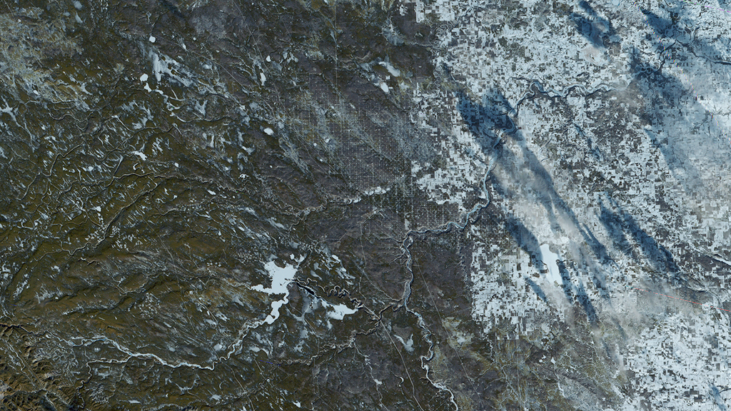 A satellite image of an area along the Canadian Highway 22, also known as the cowboy trail. The are in this image is greenish brown surrounded by the white blanket of snow to the north.