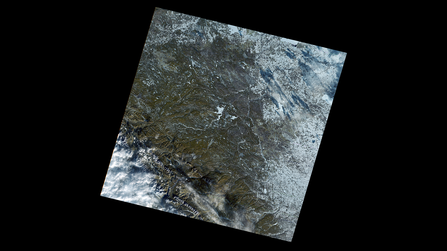 A satellite image of an area along the Canadian Highway 22, also known as the cowboy trail. The are in this image is greenish brown surrounded by the white blanket of snow to the north.