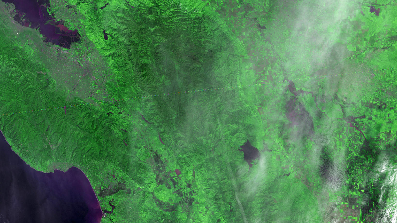 Landsat 3's first satellite image using data from the MSS scanner, featuring a slice of Northern California. This image uses infrared bands to highlight differences in land cover, with vegetation appearing in various shades of bright green.