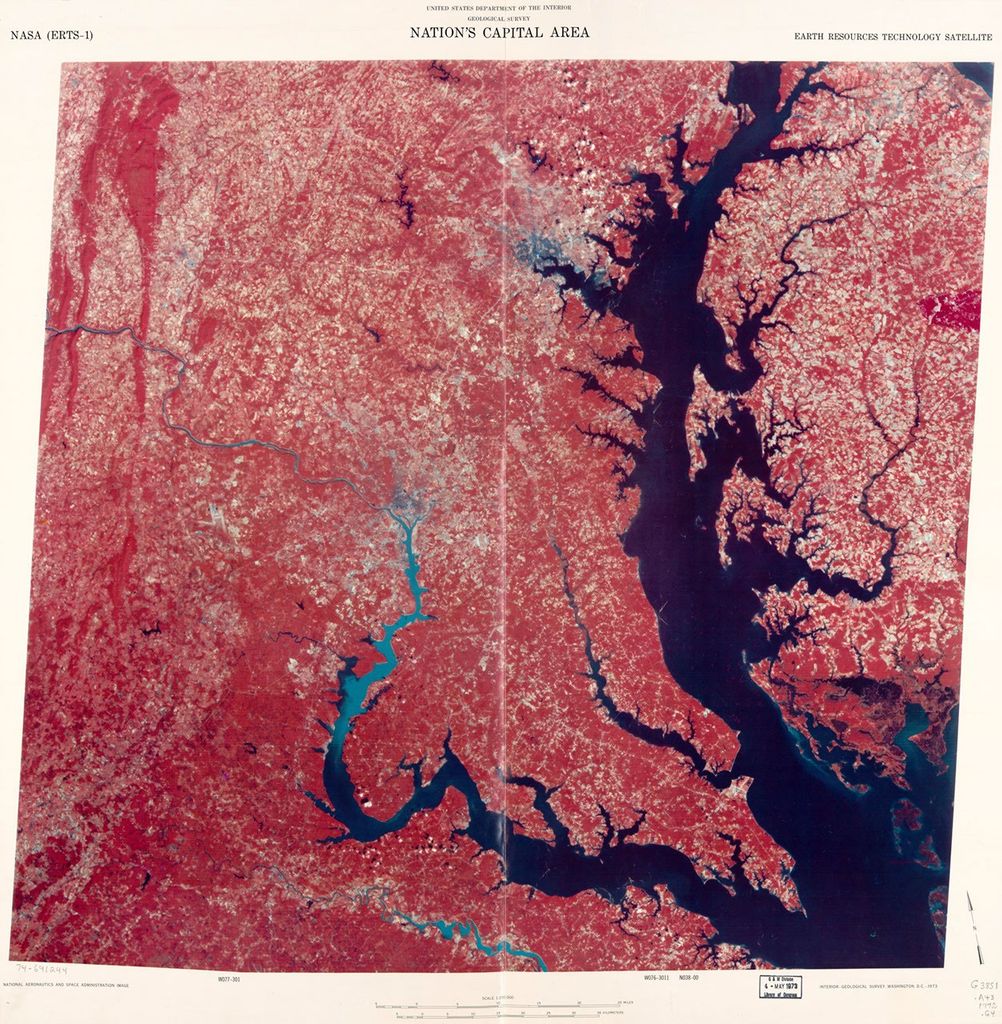 A false-color satellite image map of the Washington D.C. and Chesapeake Bay region from 1972, created using ERTS-1 (Landsat 1) data. The image shows water bodies in dark blue, vegetation in red, and developed areas in lighter tones. The distinctive shape of the Chesapeake Bay is prominently visible on the right side, with the Potomac River flowing toward Washington D.C. in the center-left portion of the image.