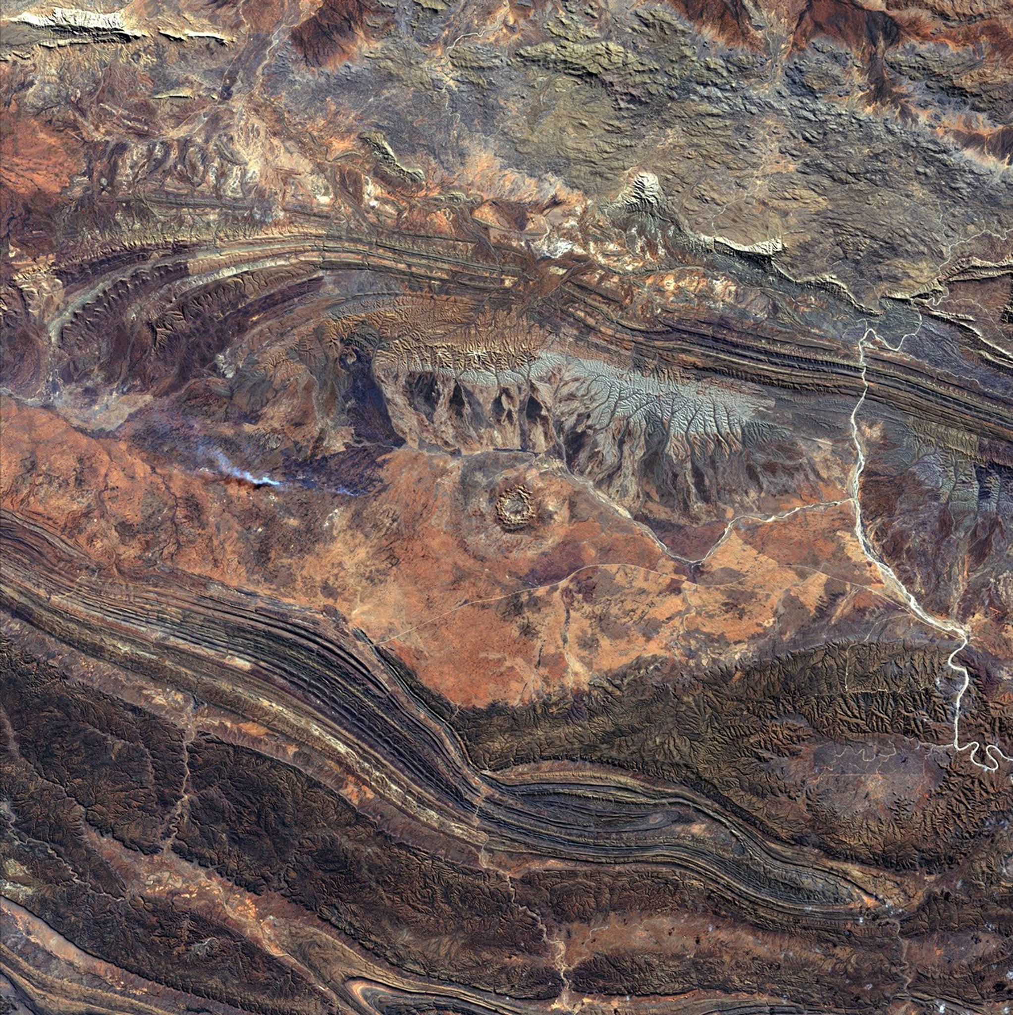 August 14th, 2002: Description: 142 million years ago, an asteroid or comet slammed into what is now the Missionary Plains in Australia’s Northern Territory, forming a crater 24 kilometers in diameter and 5 kilometers deep. Today, like a bull’s eye, the circular ring of hills that defines Gosses Bluff stands as a stark reminder of the event.