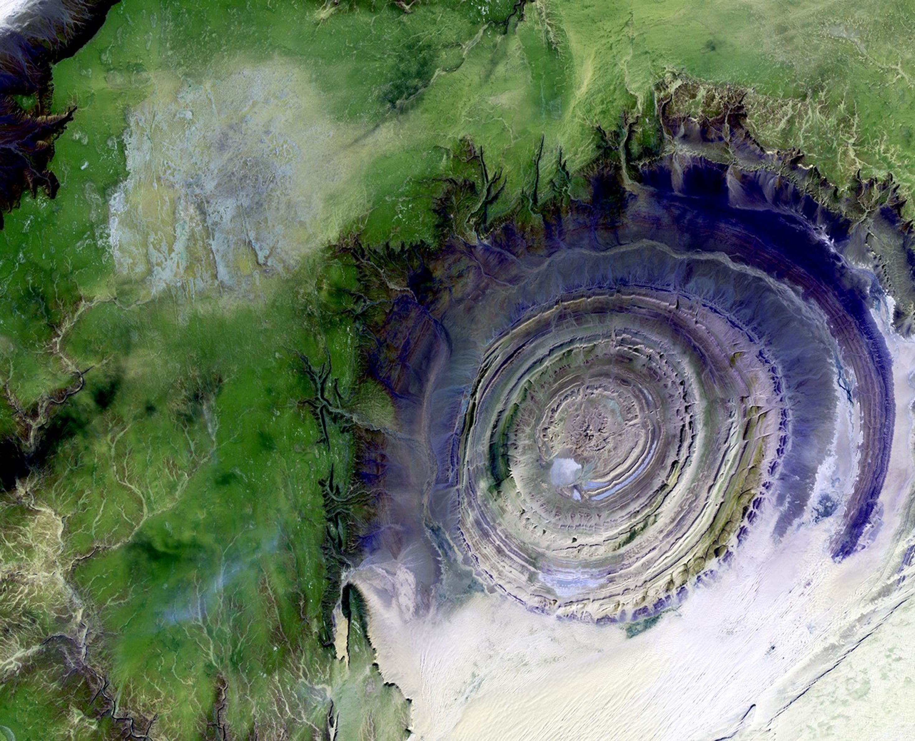 1/11/2001: The so-called Richat Structure is a geological formation in the Maur Adrar Desert in the African country of Mauritania. Although it resembles an impact crater, the Richat Structure formed when a volcanic dome hardened and gradually eroded, exposing the onion-like layers of rock.  The Richat Structure can be found on Landsat 7 WRS Path 203 Row 45, center: 21.68, -11.94.
