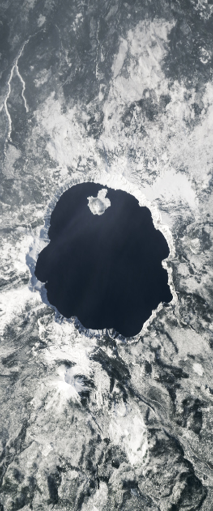 Lake surrounded by snow on top of a mountain forms the letter O in this Landsat satellite image.