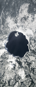 Lake surrounded by snow on top of a mountain forms the letter O in this Landsat satellite image.