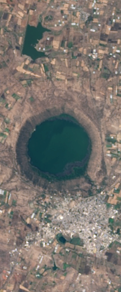 Landsat satellite image of a water filled crater in the shape of the capital letter Q.
