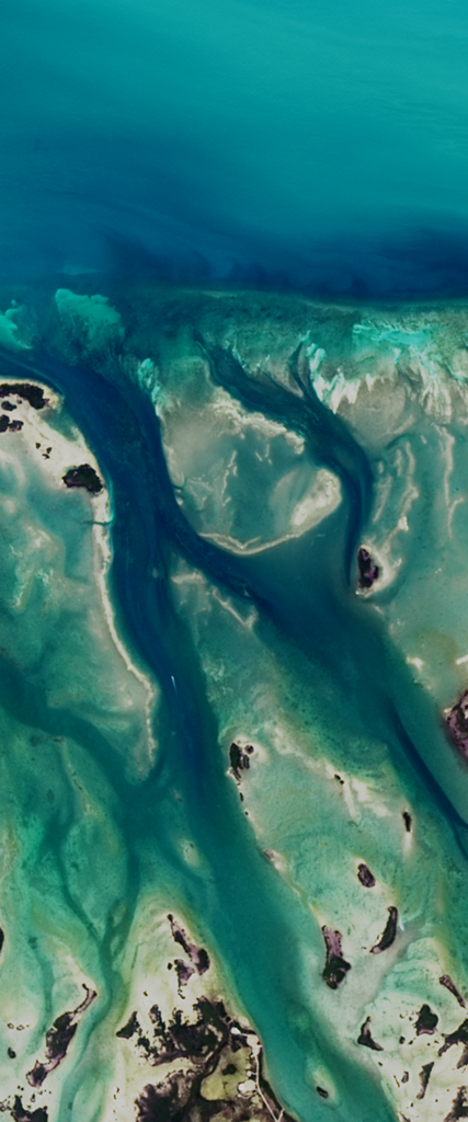 Colored water flows among coral reefs form the upper case letter R in this Landsat satellite image.