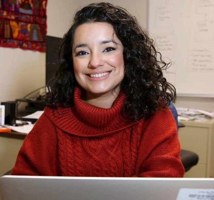 Africa Flores smiling at a desk