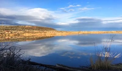 A photo of a lake reflecting a cloudy sky - the water is motionless, the reflection nearly perfect