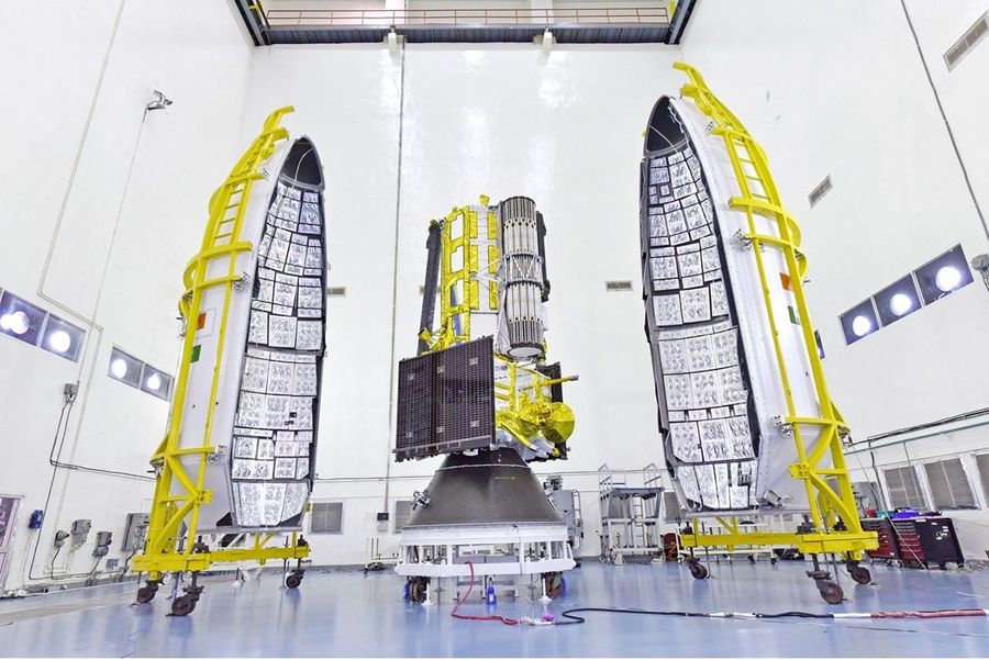 The NISAR satellite is seen with two halves of a payload fairing.