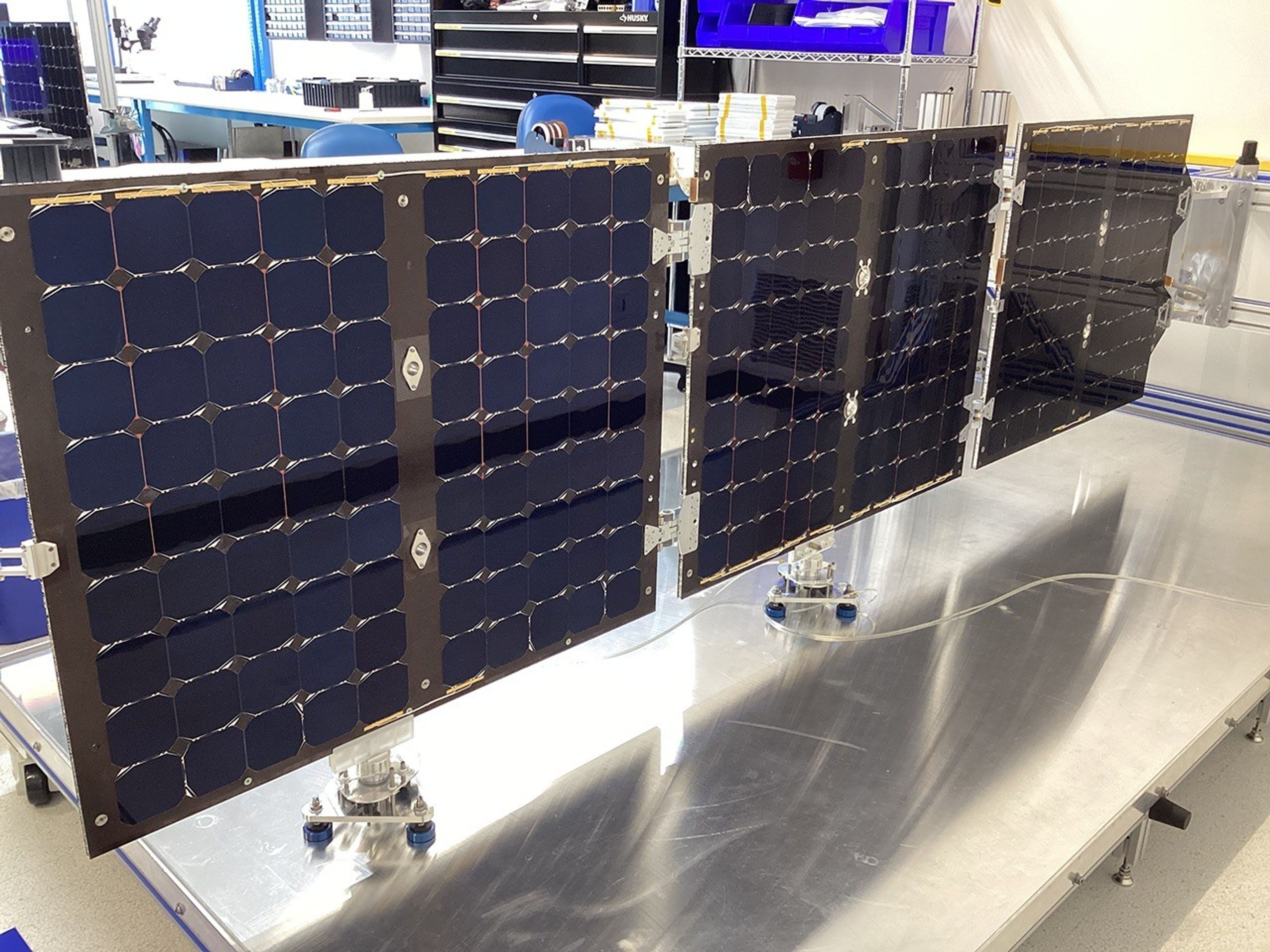 The solar panel for the Pandora mission is extended fully on a shiny metal table during testing