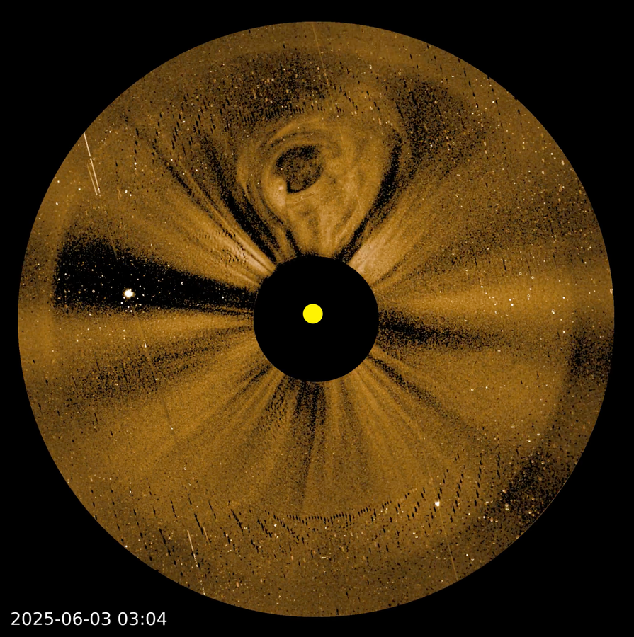 An image shows a circular view of the sky, colored gold, around the Sun. A black circular disk blocks the Sun at the center, but a small yellow circle shows the size and location of the Sun within the black disk. Near the top, a bulb-shaped cloud, a coronal mass ejection, extends upward from the Sun.