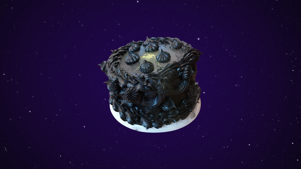 A black cake with an excess of black piping covered shimmering gold dust on a white plate in front of a starry background covered in purple haze.