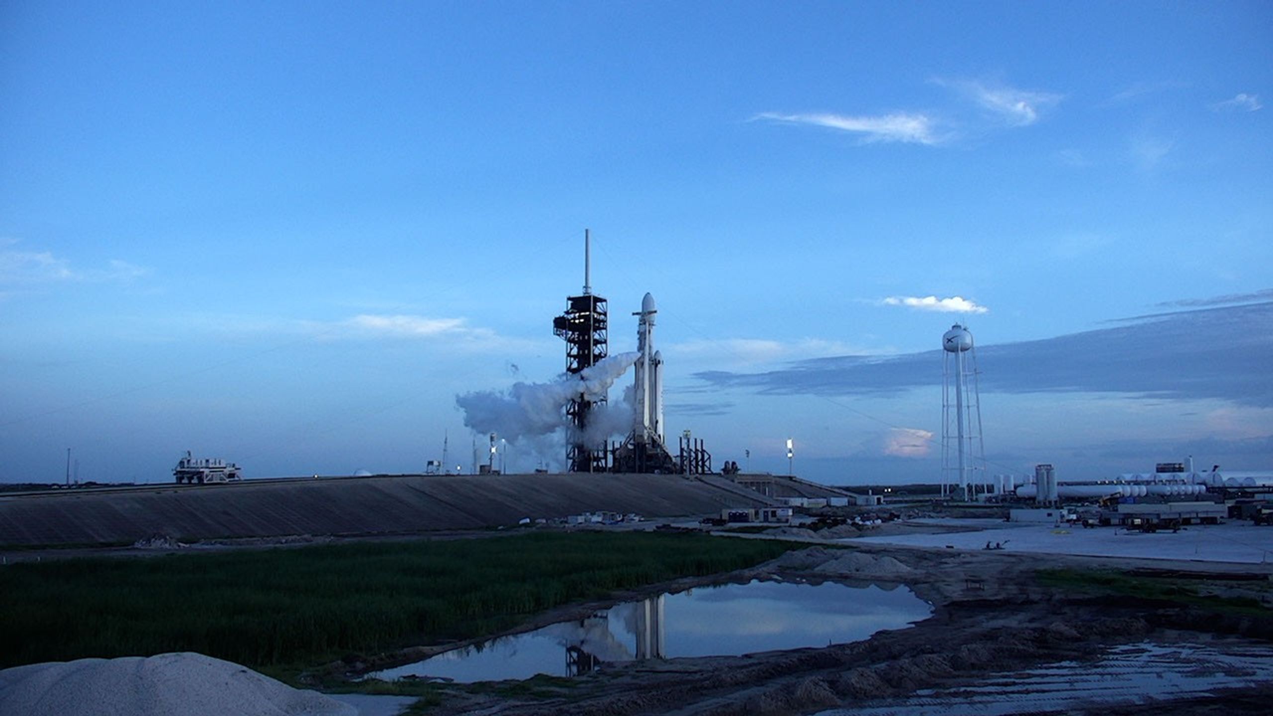 A white rocket next to a black launch tower at dawn.