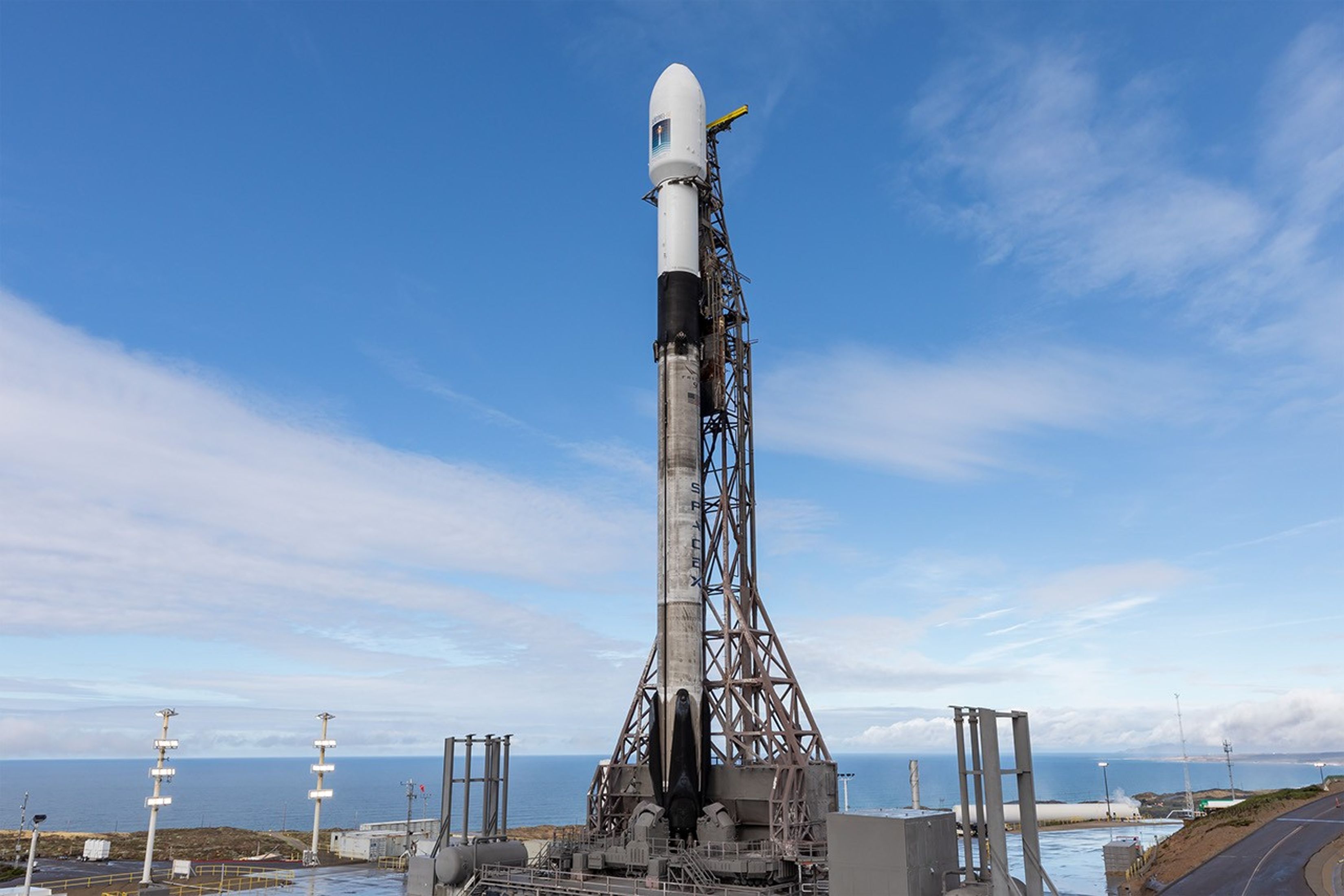 Image shows sunny skies with a rocket  with a NASA spacecraft atop standing vertical at the pad at Vandenberg Space Force Base in California on Sunday, Nov. 16, 2025