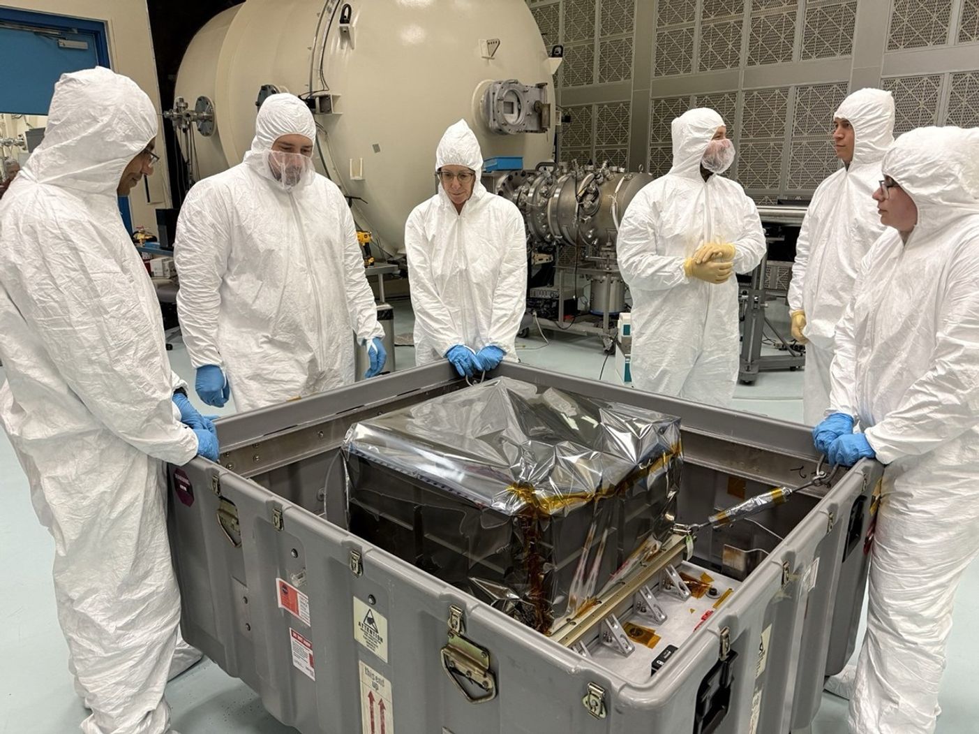 Engineers in clean suits work to unbox the StarBurst instrument at Marshall Space Flight Center