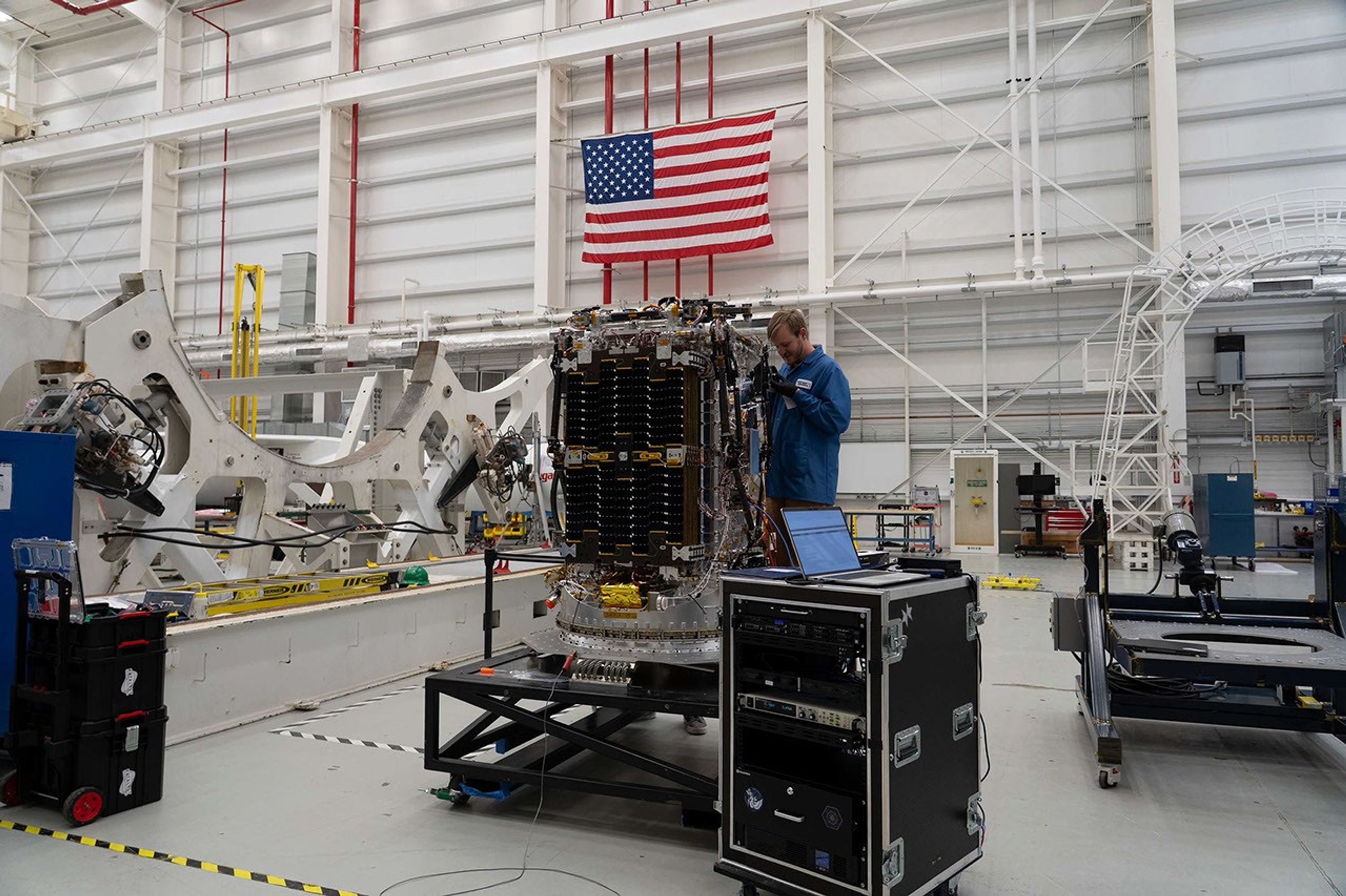 An engineer works on a small spacecraft