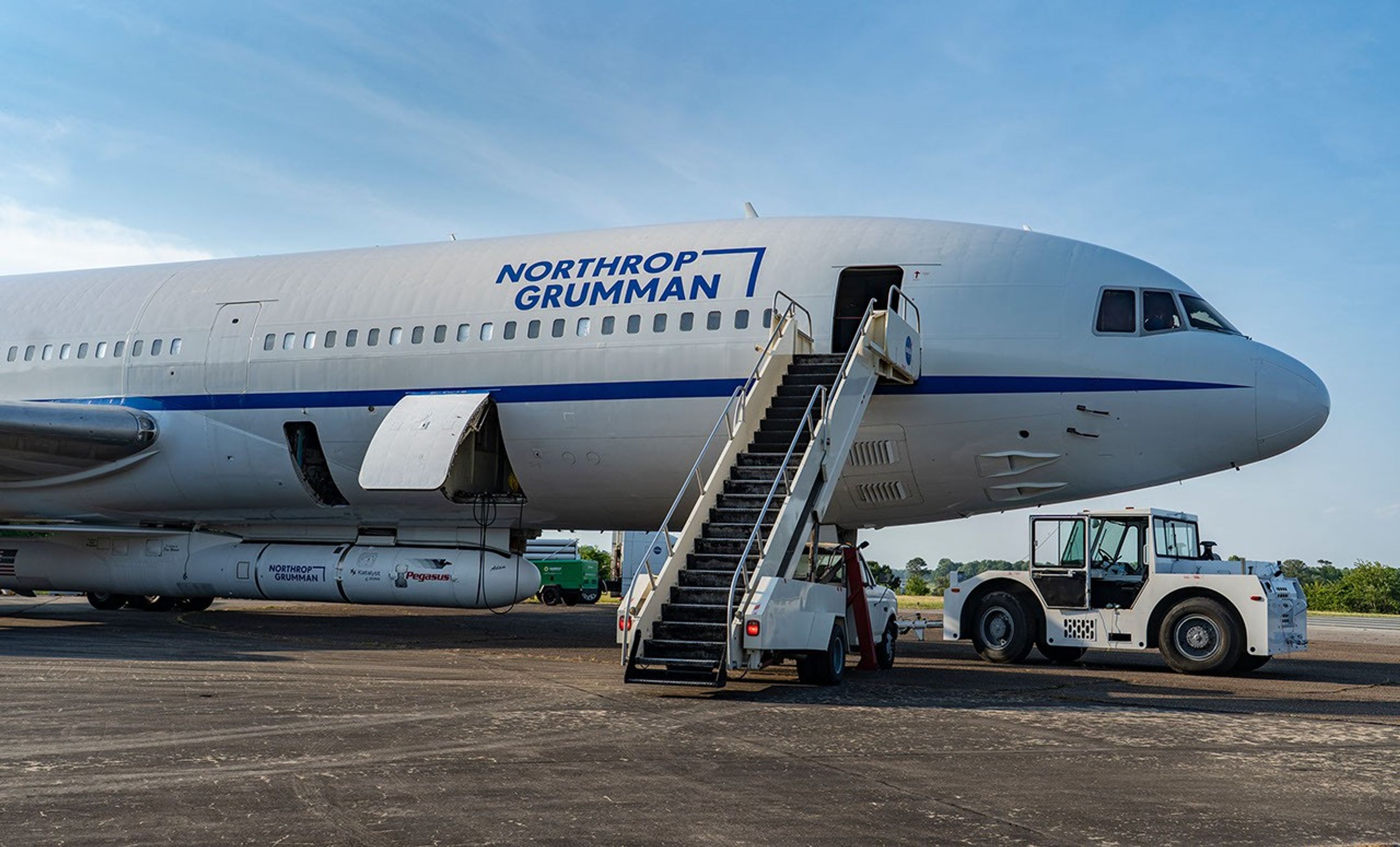 An airplane has a rocket attached to its belly and a tractor to its forward landing gear