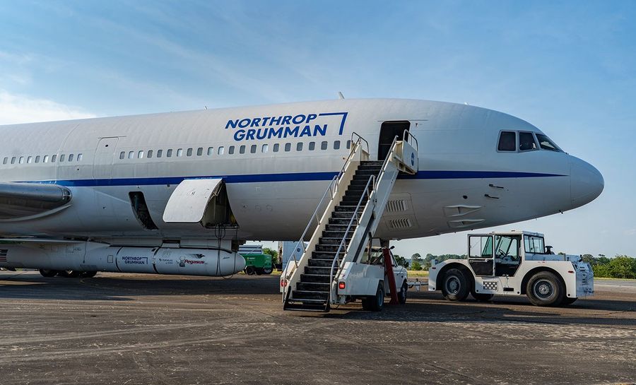 An airplane has a rocket attached to its belly and a tractor to is forward landing gear