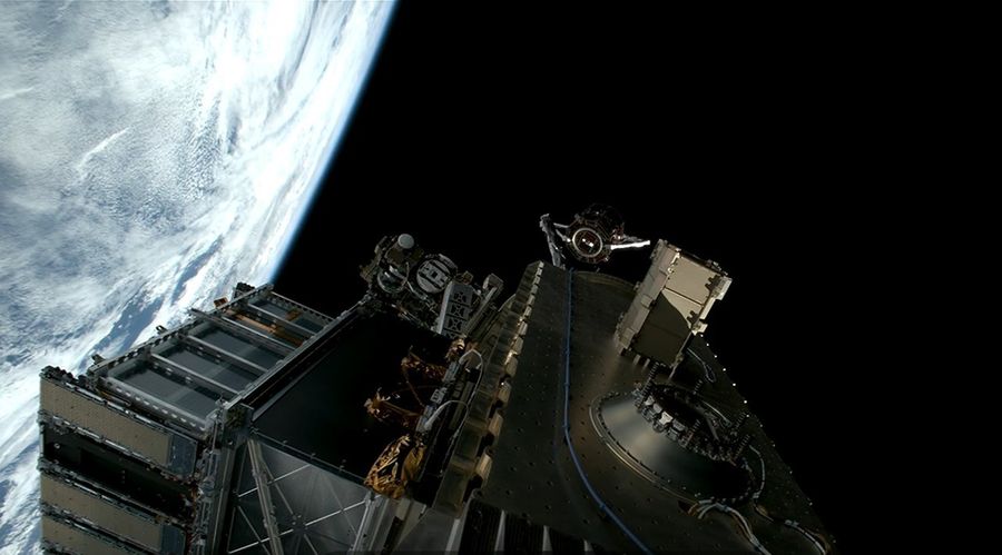 Image shows a satellite move away from a silver metallic payload with the Earth in the background