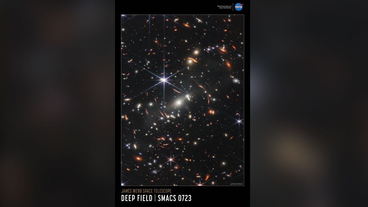 Colorful near-infrared image of the galaxy cluster SMACS 0723 outlined in white, set on a black background. The words “NIRCam Image” are set in very small white type on the bottom right of the image. The title is set below the image, along the bottom of the poster: “James Webb Space Telescope” appears in small orange type on the top line with “Deep Field SMACS 0723” in large white type on the bottom line. The poster has a portrait orientation.