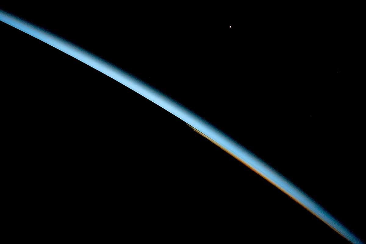 Earth's atmosphere glows from the dark surface of our planet out into the blackness of space around it.