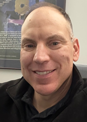 Portrait photo of Jesse Lewis with JWST poster in background