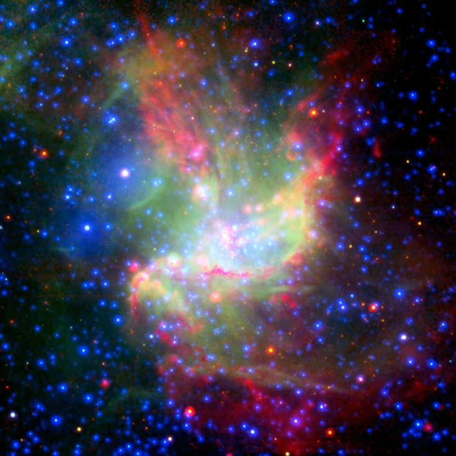 A multiwavelength view of NGC 346. The center of the image contains wispy green-yellow material, and arcs of orange and pink gas that form a boat-like shape. Among the center is a large cluster of blue-white stars.
