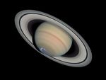 Saturn against the black background of space. The planet is made up of a very large sphere at the center, which has a range of beige, muted pink, and light green bands around it. It is surrounded by a system of rings, which extends from the top left to the bottom right of this image.