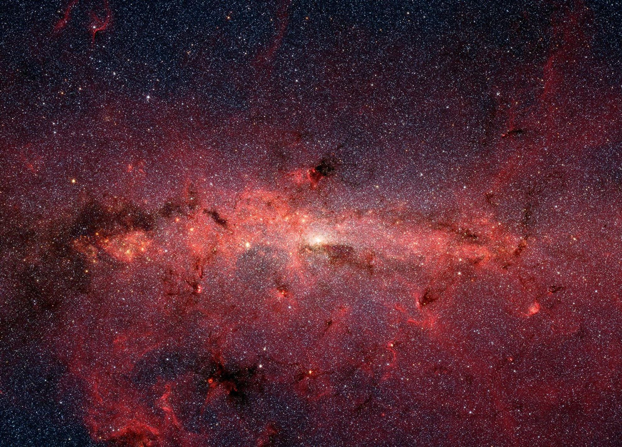 The center of our Milky Way galaxy, shown in shades of red, nearly fills the entire image with stars, gas, and dust.