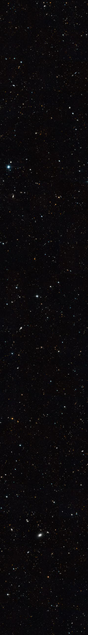 Thin horizontal Hubble image of tens of thousands of distant galaxies set against the black background of space. Most appear only as tiny dots in shades of red, orange, and white.