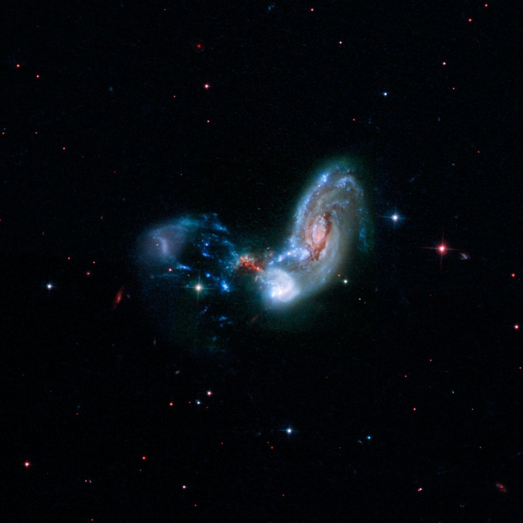Telescope image of two irregular-shaped galaxies interacting with each other.