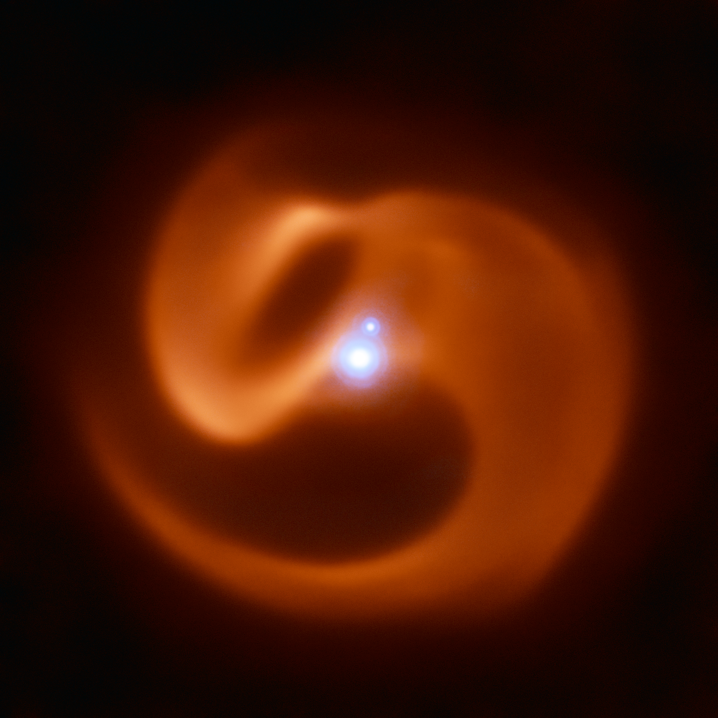 Two bright, blue-white stars appear at center, with the smaller one near 1 o’clock. They are surrounded by an orange haze that spirals and takes on undulating shapes.
