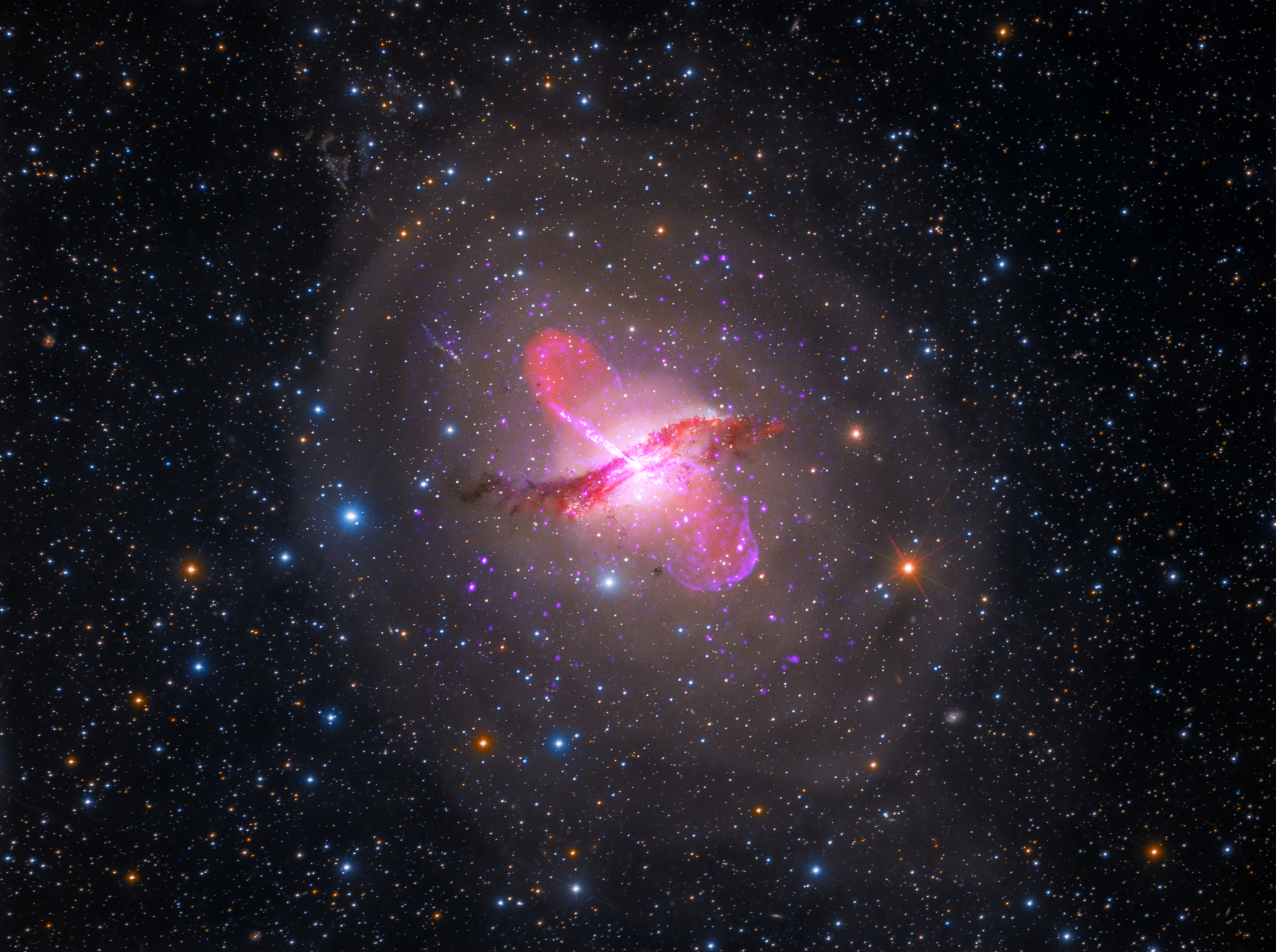 A multi-wavelength image of galaxy Centaurus A fills the field of view and is centered. The background of space is black and speckled with stars and distant galaxies of all colors.