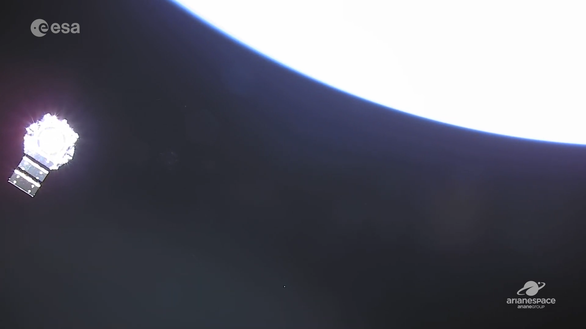 View of the bottom of NASA’s James Webb Space Telescope, with one solar panel extended to the bottom left. Earth, seen in a washed-out white, is at top right.