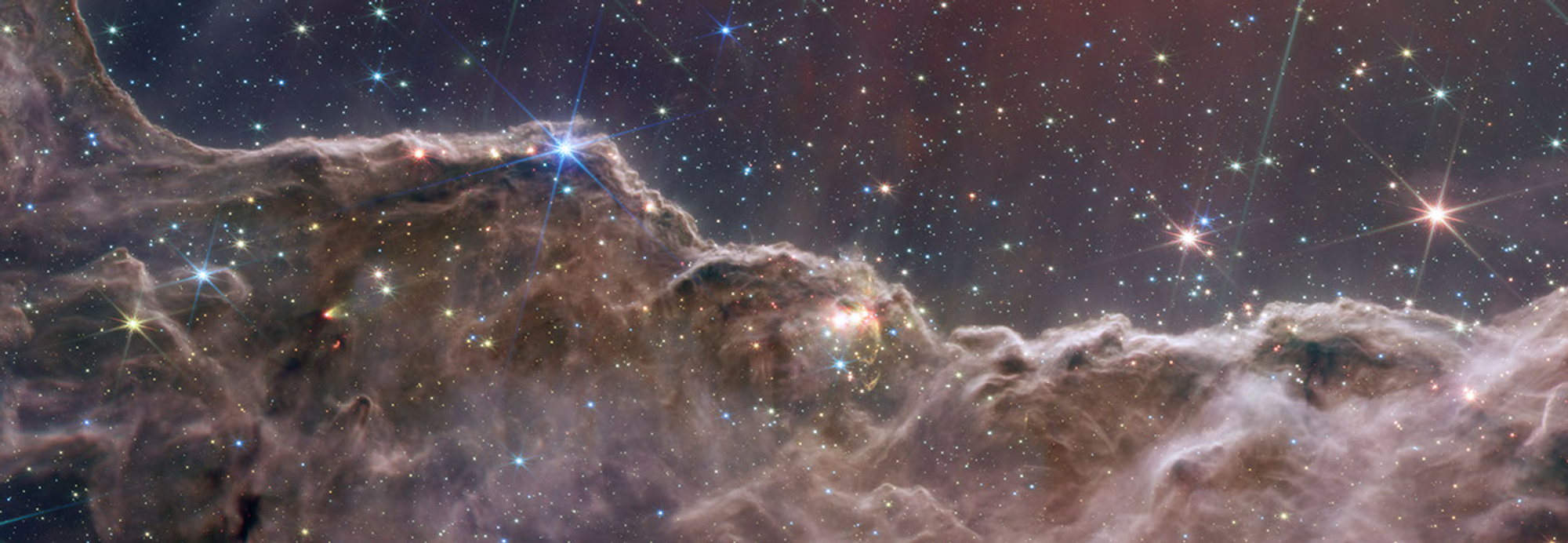 Image of a dense gray-green undulating cloudscape below a deep blue-gray starscape with scattered eight-pointed stars.