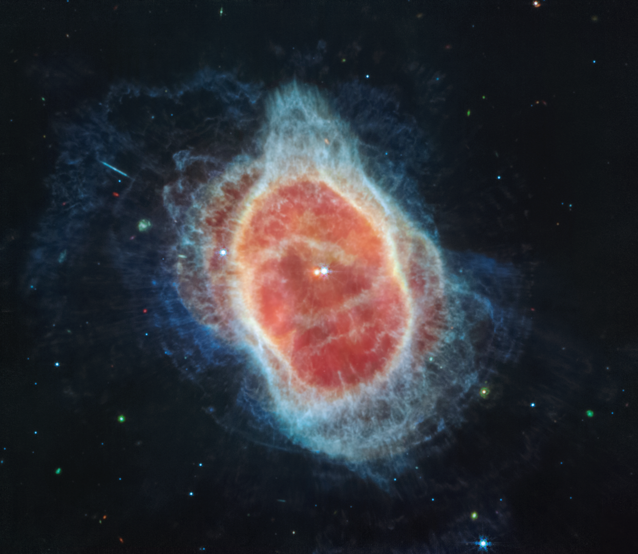 Colorful image of mid-infrared light from shells of wispy cloud-like material with two stars in the middle.