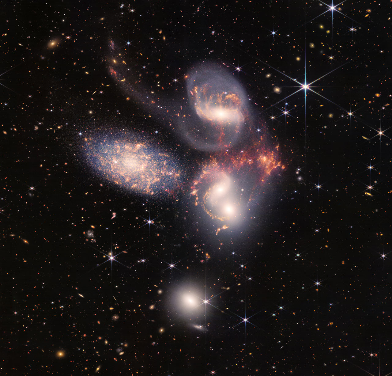Colorful image of the near- and mid-infrared light of a group of galaxies, with hundreds of background galaxies and numerous foreground stars.
