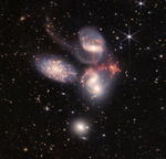 Colorful image of the near- and mid-infrared light of a group of galaxies, with hundreds of background galaxies and numerous foreground stars.