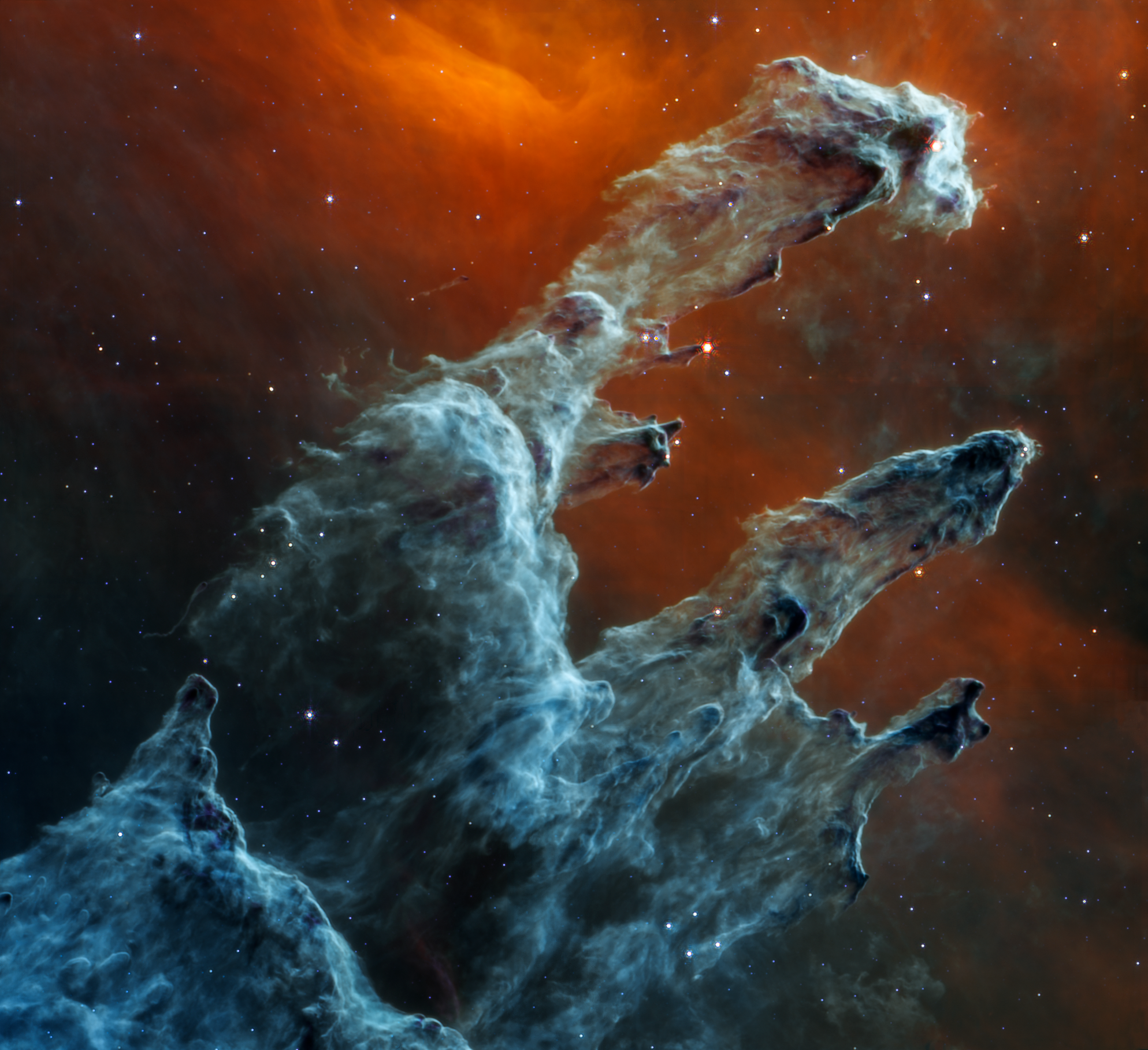 Semi-opaque layers of blue and gray gas and dust start at the bottom left and rise toward the top right. There are three prominent pillars. The left pillar is the largest and widest. The peaks of the second and third pillars are set off in darker shades of blue outlines. Few red stars appear within the pillars. Some blue and white stars dot the overall scene.