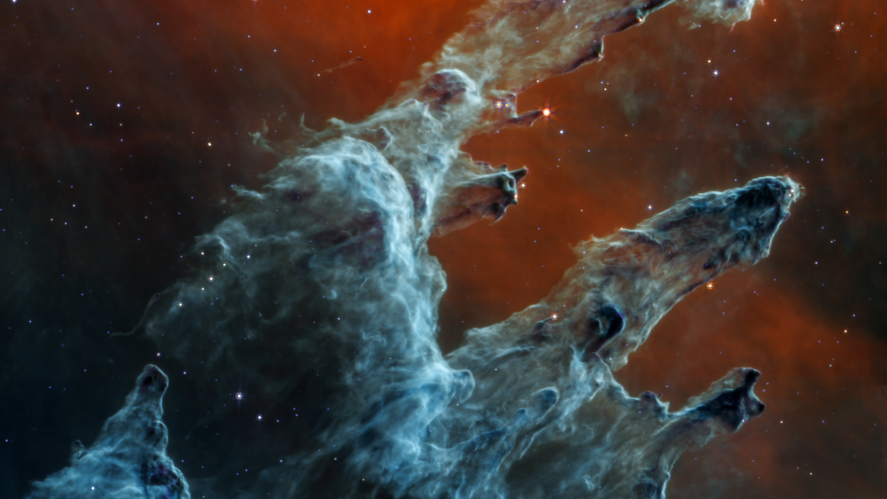 The video starts zoomed in to the center of the image, which shows semi-opaque layers of blue and gray gas and dust in three prominent pillars. The left pillar is the largest and widest. The peaks of the second and third pillars are set off in darker shades of blue. Few red stars appear within the pillars. Some blue and white stars dot the overall scene. At 17 seconds, the screen dissolves to show Webb’s near-infrared image, which has layers of semi-opaque rusty red colored gas and dust that also form three prominent pillars. At the edges of the pillars are wavy red lines that look like lava. At 28 seconds, the video transitions back to the mid-infrared image, zooming in toward the top of the frame. At 46 seconds, three labels that each read young star appear toward the left of the frame, pointing to the edges of the pillars. At 52 seconds, three stars that appear whiter and outside the pillars are labeled aging star. At 58 seconds, a circle highlights a bright red star at the right edge of the topmost pillar