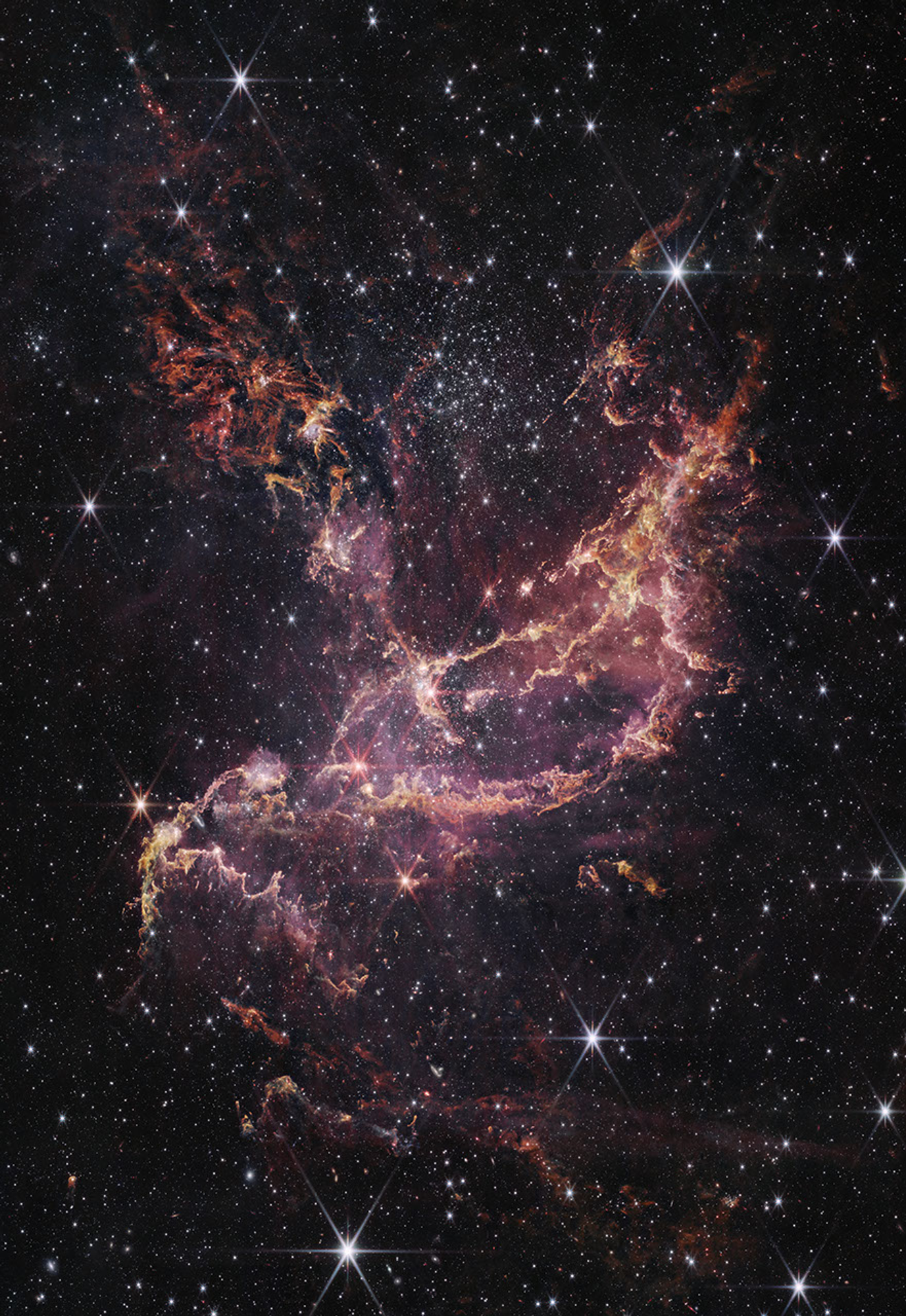 A star cluster within a nebula. The center of the image contains arcs of orange and pink gas that form a boat-like shape. One end of these arcs points to the top right of the image, while the other end points toward the bottom left. Another plume of orange and pink gas expands from the center to the top left of the image. To the right of this plume is a large cluster of white stars. There are more of these white stars and a few galaxies of different sizes spread throughout the image.