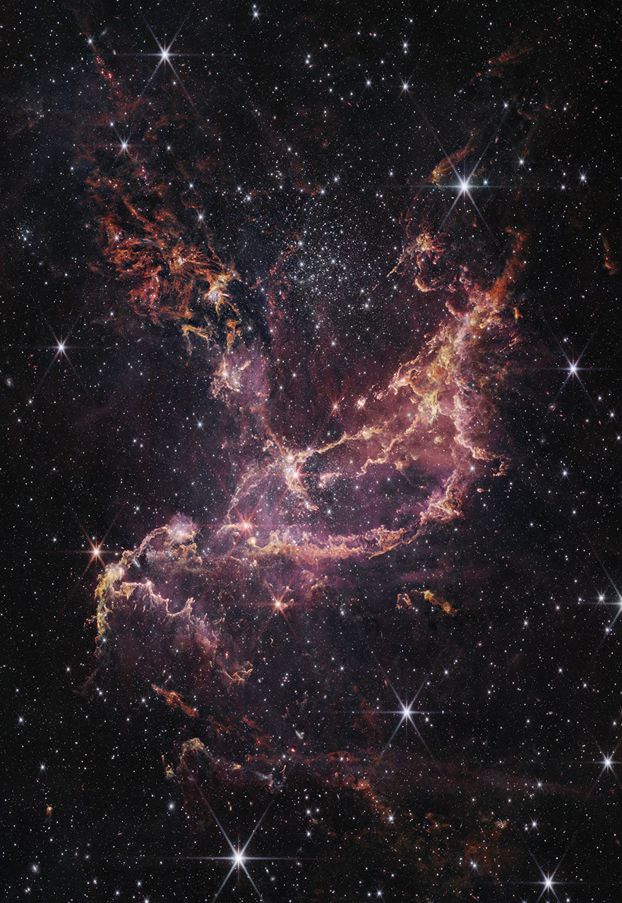 A star cluster within a nebula. The center of the image contains arcs of orange and pink gas that form a boat-like shape. One end of these arcs points to the top right of the image, while the other end points toward the bottom left. Another plume of orange and pink gas expands from the center to the top left of the image. To the right of this plume is a large cluster of white stars. There are more of these white stars and a few galaxies of different sizes spread throughout the image.