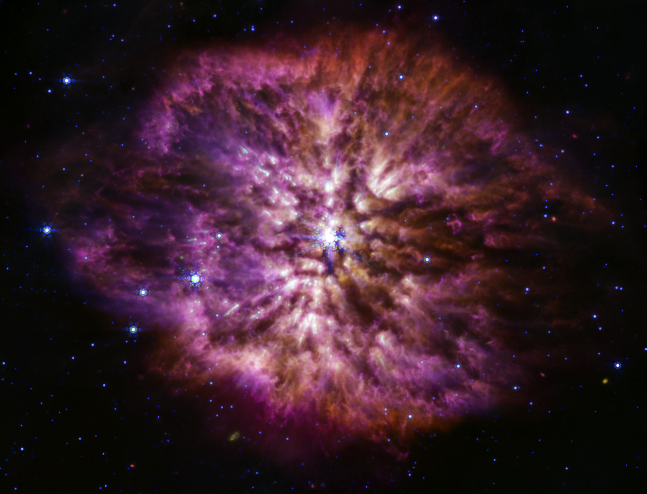 A large, bright star shines from the center with smaller stars scattered throughout the image. A clumpy cloud of material surrounds the central star, with more material above and below than on the sides, in some places allowing background stars to peek through. The cloud material is yellow closer to the star, and turns purple at its outer edges.